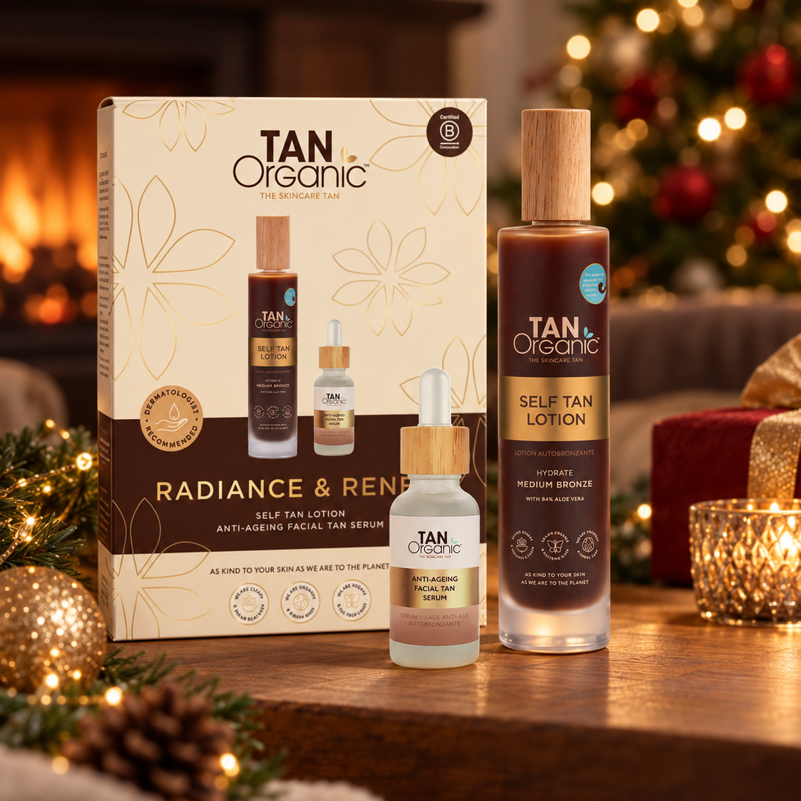 TanOrganic Radiance &amp; Renew gift set with Self Tan Lotion and Anti Ageing Facial Tan Serum beside a Christmas tree and lit fireplace.